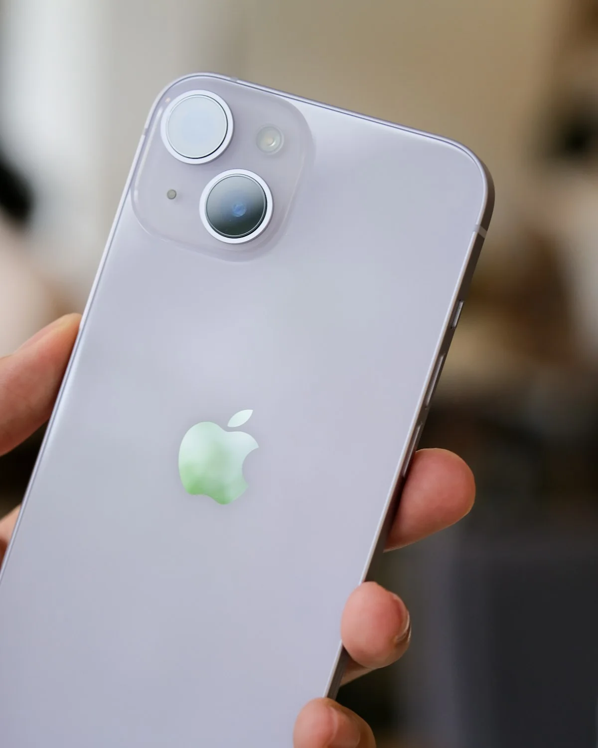 Eine Hand hält ein helles Smartphone mit der Rückseite zur Kamera.