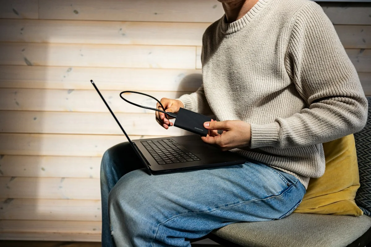 Eine Person verbindet ein externes Speicherlaufwerk mit einem Laptop.