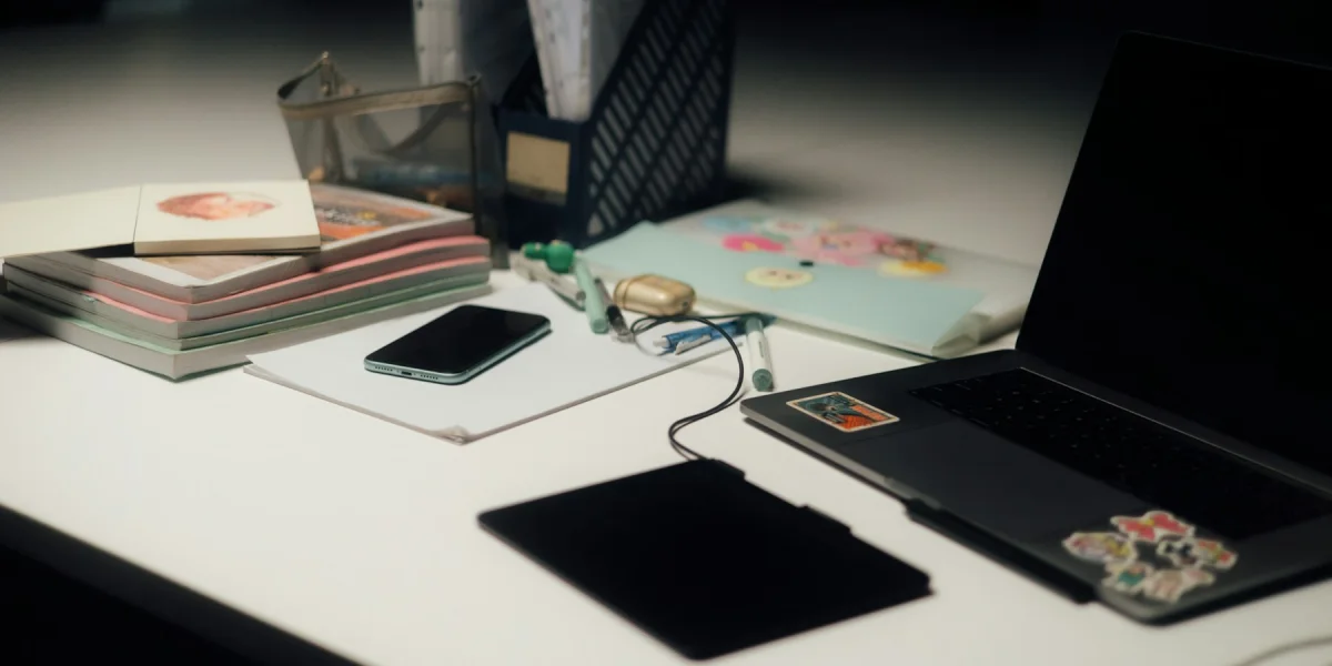 Überfüllter Schreibtisch mit Notebook, Smartphone, Papieren und Schreibutensilien