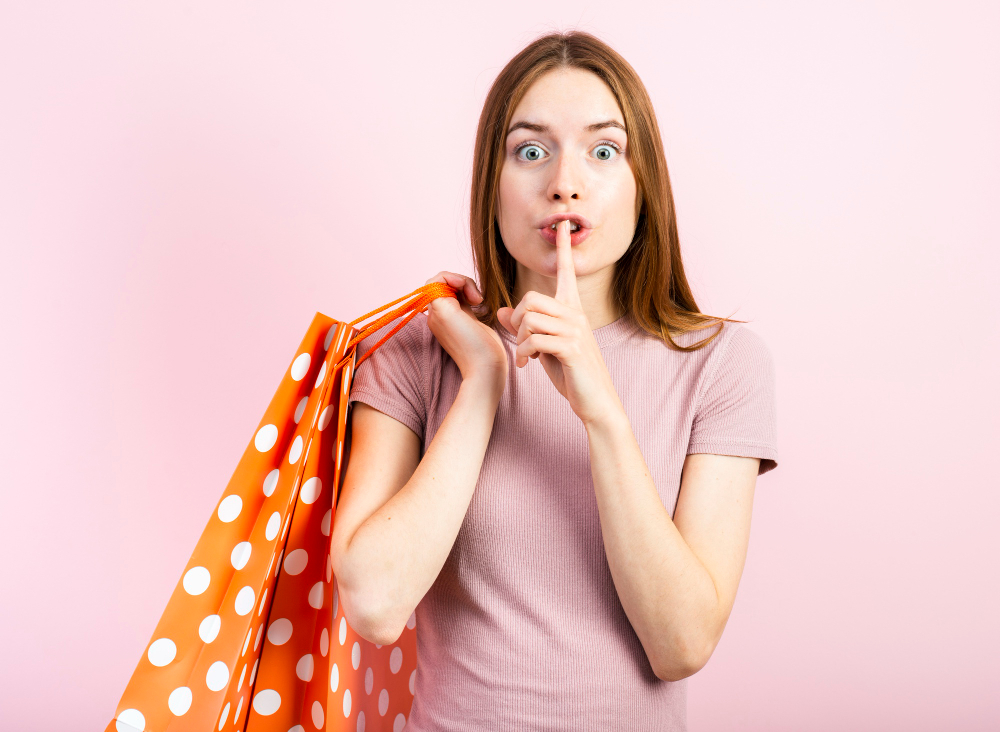 Frau mit Einkaufstüten die sich den Finger vor dem Mund hält und damit beschreiben möchte, dass man nichts sagen soll.