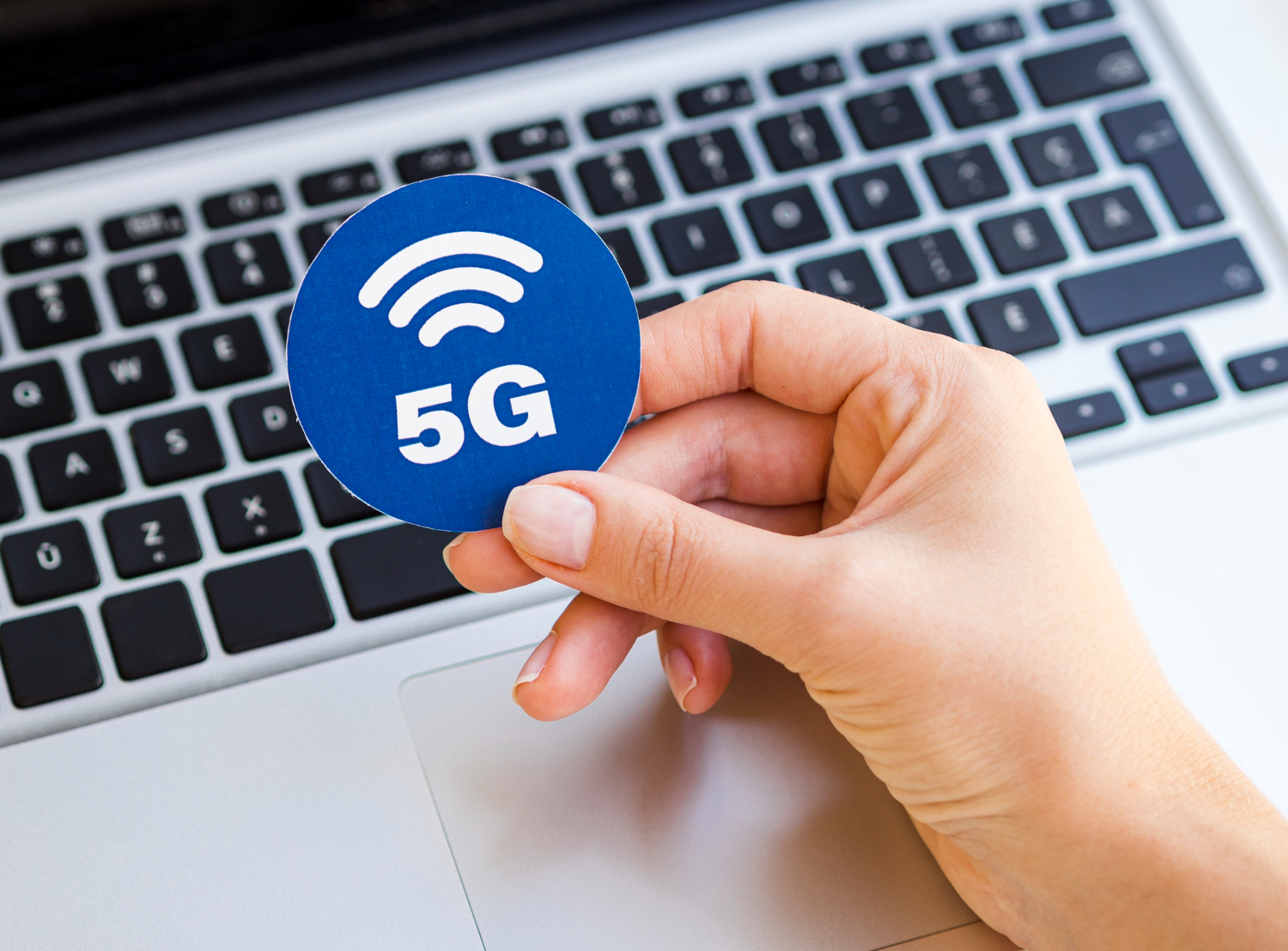 langsames Internet man sieht einen Laptop und eine Hand die ein Zeichen in der Hand hält wo 5G draufsteht.