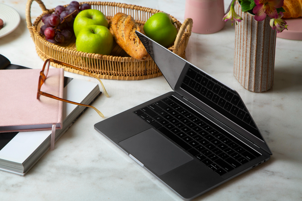 Macbook auf einem Tisch neben Obst