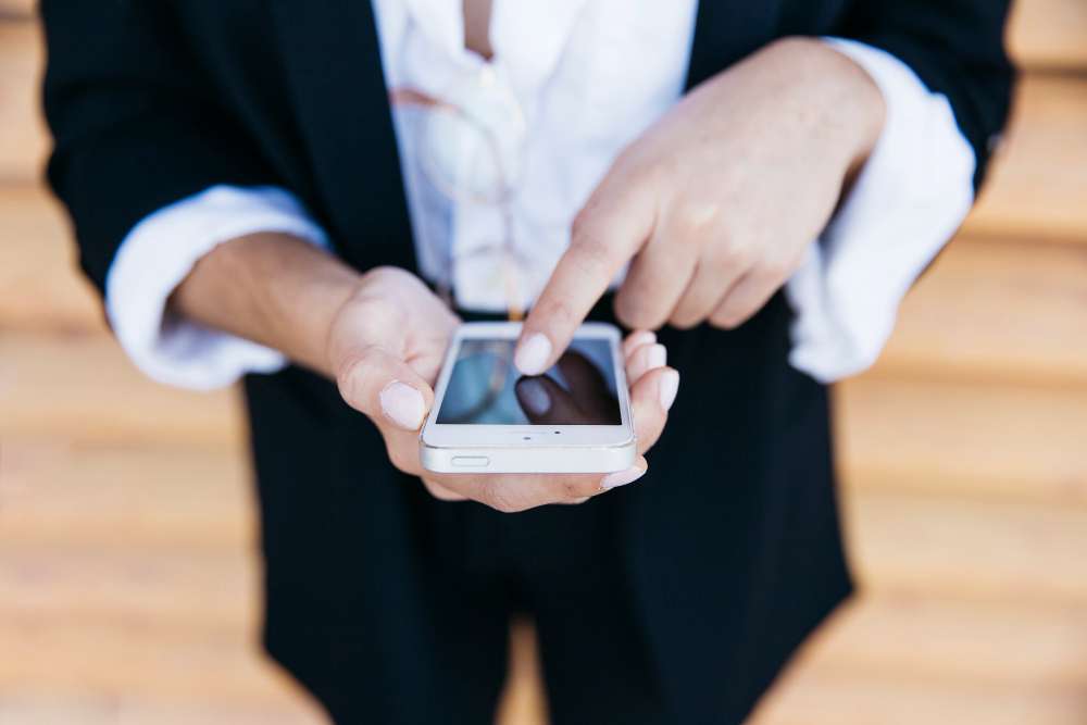 Handy in der Hand von einem Menschen und dieser tippt mit einem Finger